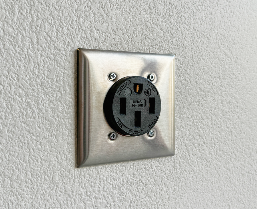 A NEMA 14-50 EV or range outlet on a wall. The bottom slot is a straight bar.