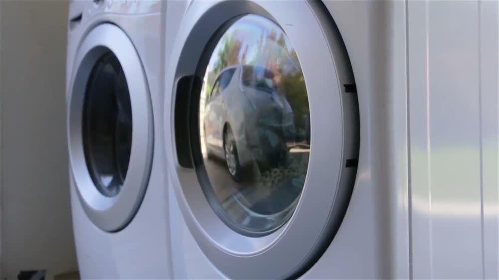 Charging cable being plugged into an EV beside a laundry machine