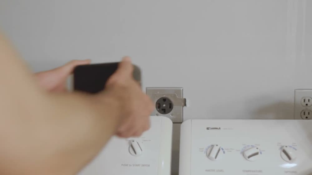 A 240V dryer outlet on a wall behind a washer and dryer